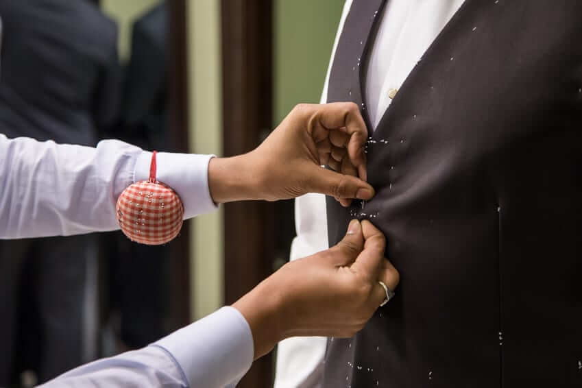 A tailor's hands carefully working on a suit jacket